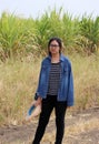 Woman agriculturist standing with straw hat in hand and wearing Long sleeve denim shirt on the sugarcane farm background