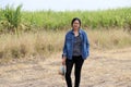 Woman agriculturist standing with straw hat in hand and wearing Long sleeve denim shirt on the sugarcane farm background