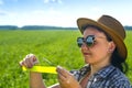 A woman agronomist in sunglasses and a hat measures the parameters of crops.