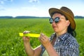 A woman agronomist in sunglasses and a hat measures the parameters of crops.