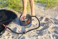 A woman with air foot pump pumps an inflatable mattress or air bed at sandy beach. Foot inflates air mattress with foot Royalty Free Stock Photo