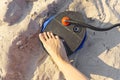 A woman with air foot pump pumps an inflatable mattress or air bed at sandy beach. Foot inflates air mattress with foot Royalty Free Stock Photo