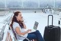 Woman in airport talking by phone and checking emails on laptop, business travel