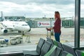 Woman at the airport window and flight departure, Airport Terminal: Happy Traveling Looks Around. Frankfurt am Main