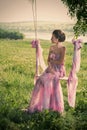 Woman in airy pink dress on the swings