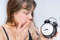 Woman with alarm clock comes late to work because she oversleep