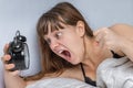 Woman with alarm clock comes late to work because she oversleep