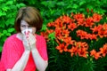 woman with an allergic rhinitis near lilies in nature