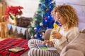 Woman alone at home eating cookies and drinking tea or coffe with the christmas tree at the background the christmas day - adult