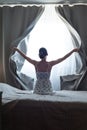 Woman alone at home , opens the curtains letting in bright ray of sunlight Royalty Free Stock Photo