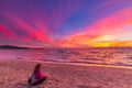 Woman alone relaxing on sand beach romantic sky at sunset. Real people getting away from it all. Dramatic clouds over waving sea Royalty Free Stock Photo