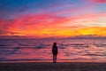 Woman alone relaxing on sand beach romantic sky at sunset. Real people getting away from it all. Dramatic clouds over waving sea Royalty Free Stock Photo