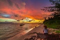 Woman alone relaxing on sand beach romantic sky at sunset, rear view, golden cloudscape, real people. Indonesia, Sumatra, tropical Royalty Free Stock Photo