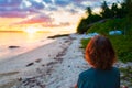 Woman alone relaxing on sand beach romantic sky at sunset, rear view, golden cloudscape, real people. Indonesia, Sumatra, tropical Royalty Free Stock Photo