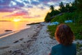 Woman alone relaxing on sand beach romantic sky at sunset, rear view, golden cloudscape, real people. Indonesia, Sumatra, tropical Royalty Free Stock Photo