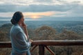 Woman alone on terrace watching sunset over mountains during summer vacation