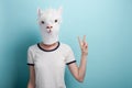 Woman in alpaca mask with hand peace victory freedom sign