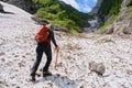 Woman alpinist with ice axe, crampons and backpack, hikes up on late Summer snow in the White Valley, an unmarked alpine route.