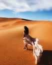 Woman in amazing silk wedding dress, view of Sahara desert sand dunes at sunset Royalty Free Stock Photo