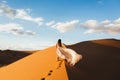 Woman in amazing silk wedding dress, view of Sahara desert sand dunes at sunset Royalty Free Stock Photo