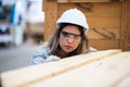 woman American African wearing safety uniform and hard hat working quality inspection of wooden products at workshop manufacturing