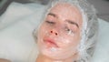 Woman with anesthesia cream and film on her face before PRP therapy procedure.