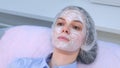 Woman with anesthetic cream on face skin before biorevitalization for numbing.