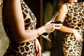 Woman in animal print dress with a glass of red wine in her hands looks at her reflection in the mirror.