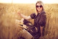 Woman in animal print dress, straw hat in front of Sun in middle of wheat field with pleasure , enjoying summer holidays