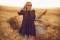 woman in animal print dress, straw hat in front of Sun in middle