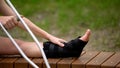 Woman with ankle brace holding crutch sitting outdoors, trauma bandage, health Royalty Free Stock Photo