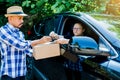 Woman appending signature sign on smartphone after accepting receive boxes from delivery man in car