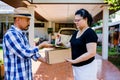 Woman appending signature sign on tablet after accepting receive boxes from delivery man at home