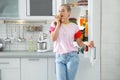 Woman with apple standing near open refrigerator