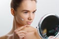 The woman applies face cream. Woman and mirror. Portrait of beautiful young woman with cream on her face