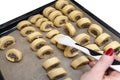 A woman applies oil to freshly made, raw yeast cakes with mushrooms inside using a silicone cooking trowel.