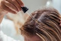 Woman applies oil to her hair with pipette. Beauty caring for scalp and hair.