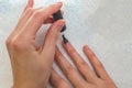 A woman applies a primer to her nails before applying varnish. Close-up of a hand.