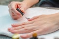 A woman applies a primer to her nails before applying varnish. Close-up of a hand.