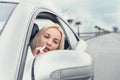 Woman apply rose lipstick looking in car mirror