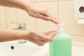 Woman applying antiseptic gel on hand in public bathroom Royalty Free Stock Photo
