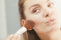 Woman applying bronzing powder with brush to her skin Royalty Free Stock Photo