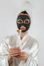 Woman applying with brush black clay mud facial mask  on white Royalty Free Stock Photo