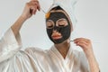 Woman applying with brush black clay mud facial mask  on white Royalty Free Stock Photo