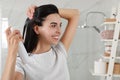 Woman applying dry shampoo onto her hair in bathroom Royalty Free Stock Photo