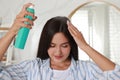 Woman applying dry shampoo onto her hair near mirror indoors Royalty Free Stock Photo