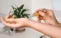 Woman applying essential oil on wrist indoors