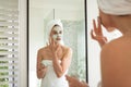 Woman applying face pack while looking in the mirror Royalty Free Stock Photo