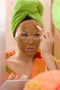 Woman applying facial mask from brown clay
