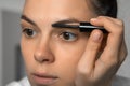 Woman is applying fixing gel on eyebrows using brush, closeup face. Royalty Free Stock Photo